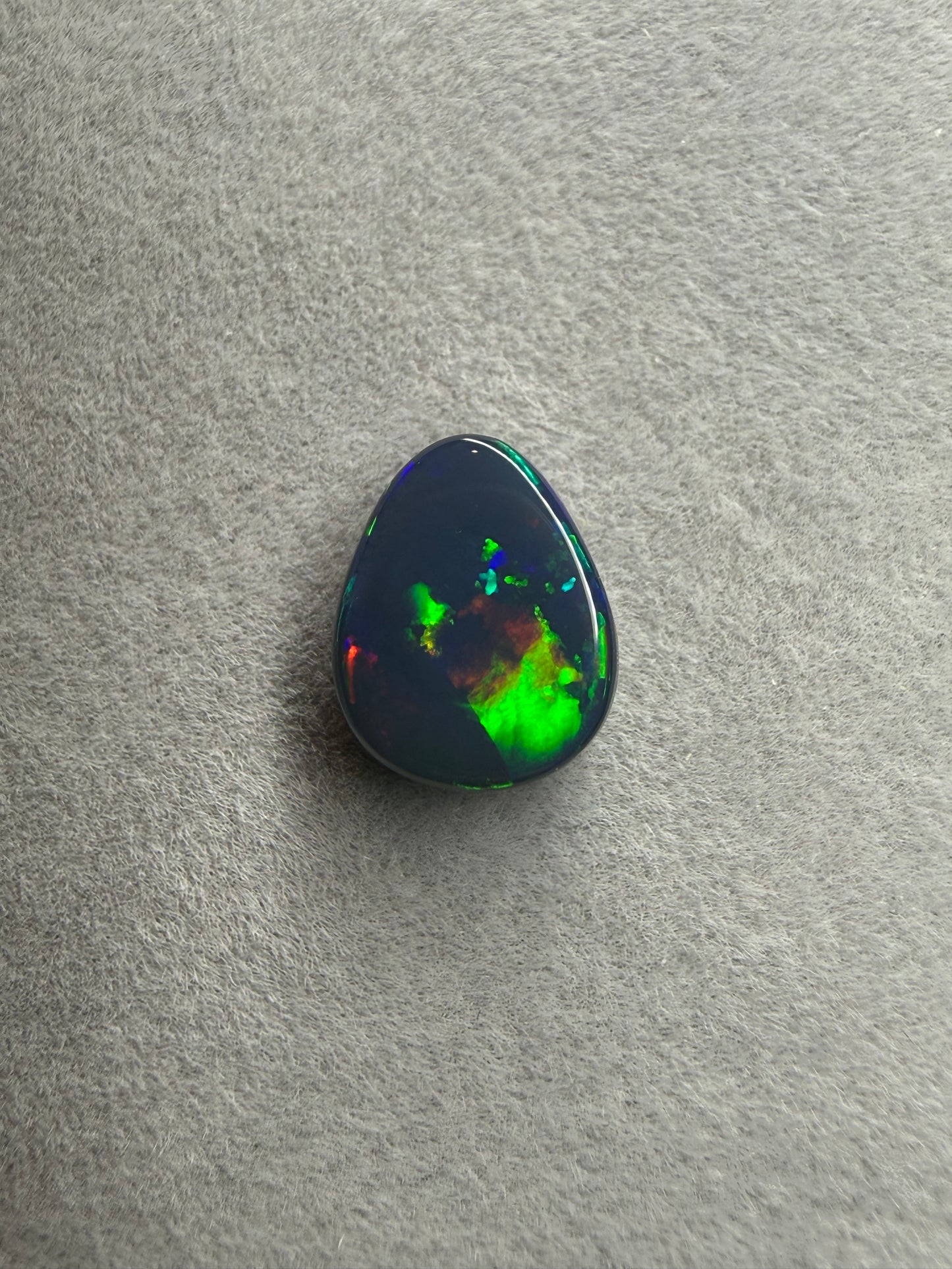 Seltener australischer Black Opal aus Lightning Ridge mit 2 Karat, Tropfenform und brillantem Farbspiel in Blau, Grün, Gelb, Orange und Rot.