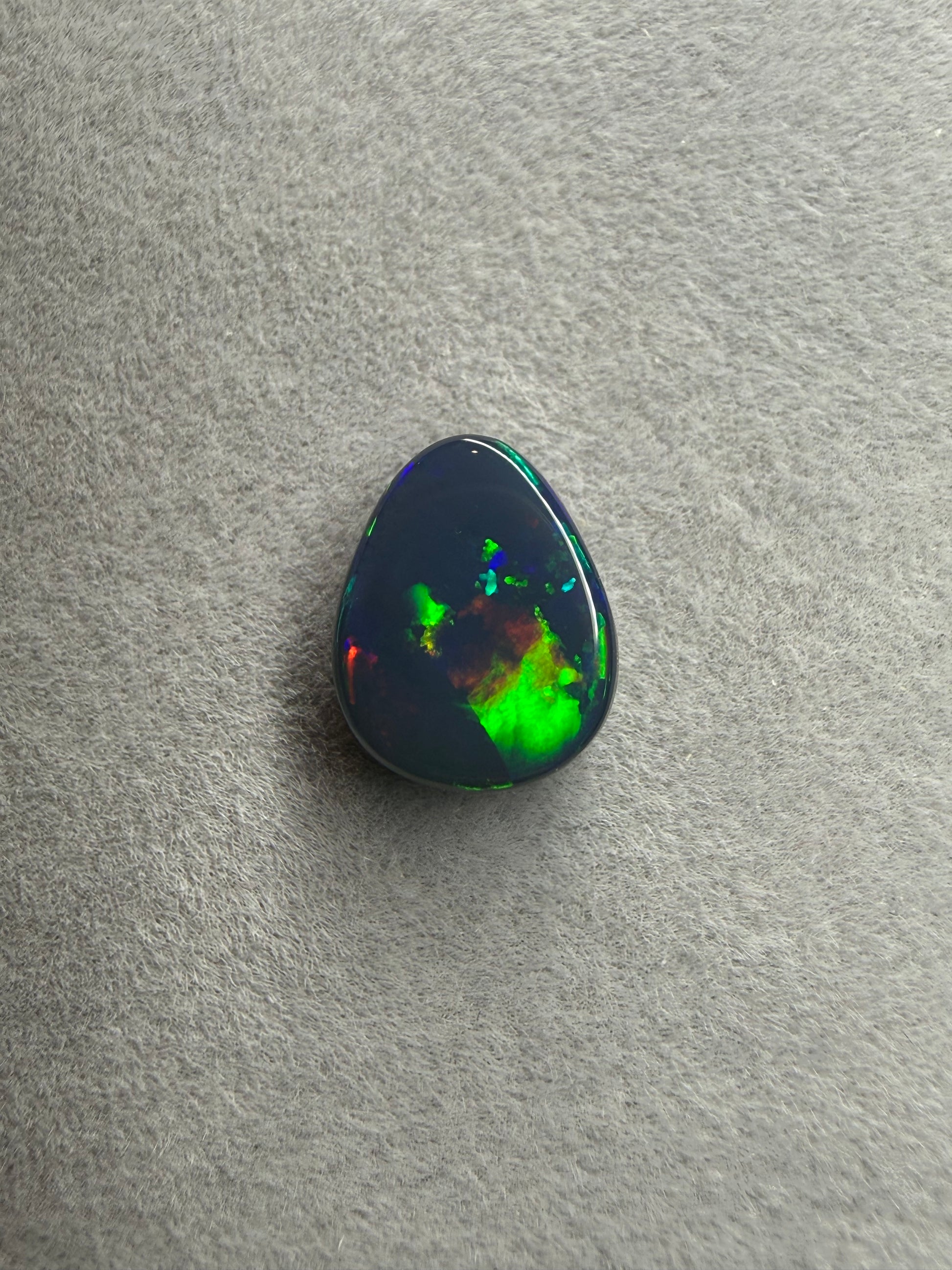 Seltener australischer Black Opal aus Lightning Ridge mit 2 Karat, Tropfenform und brillantem Farbspiel in Blau, Grün, Gelb, Orange und Rot.