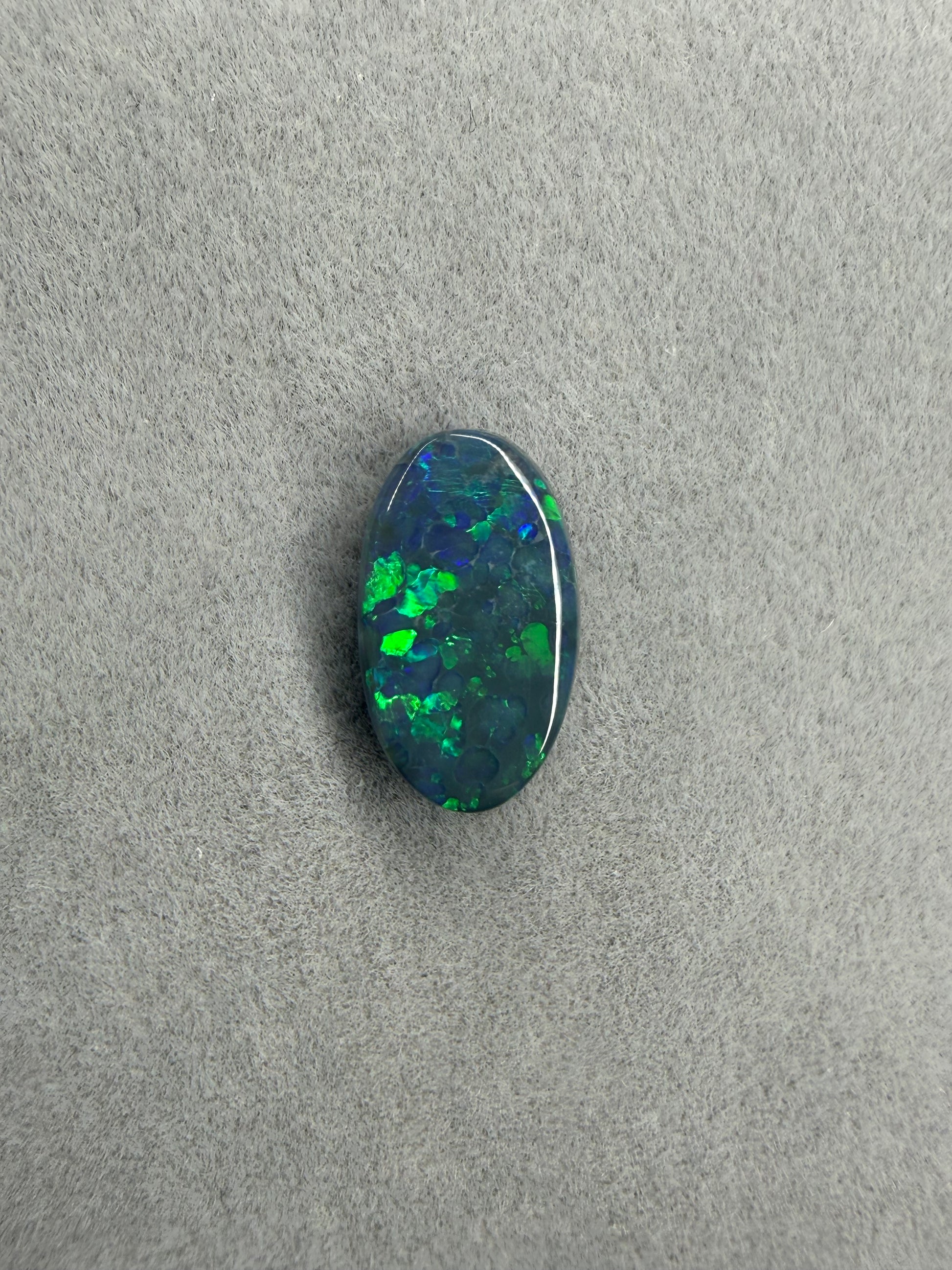 Natürlicher Solid Black Opal mit leuchtenden grünen und blauen Reflexen.