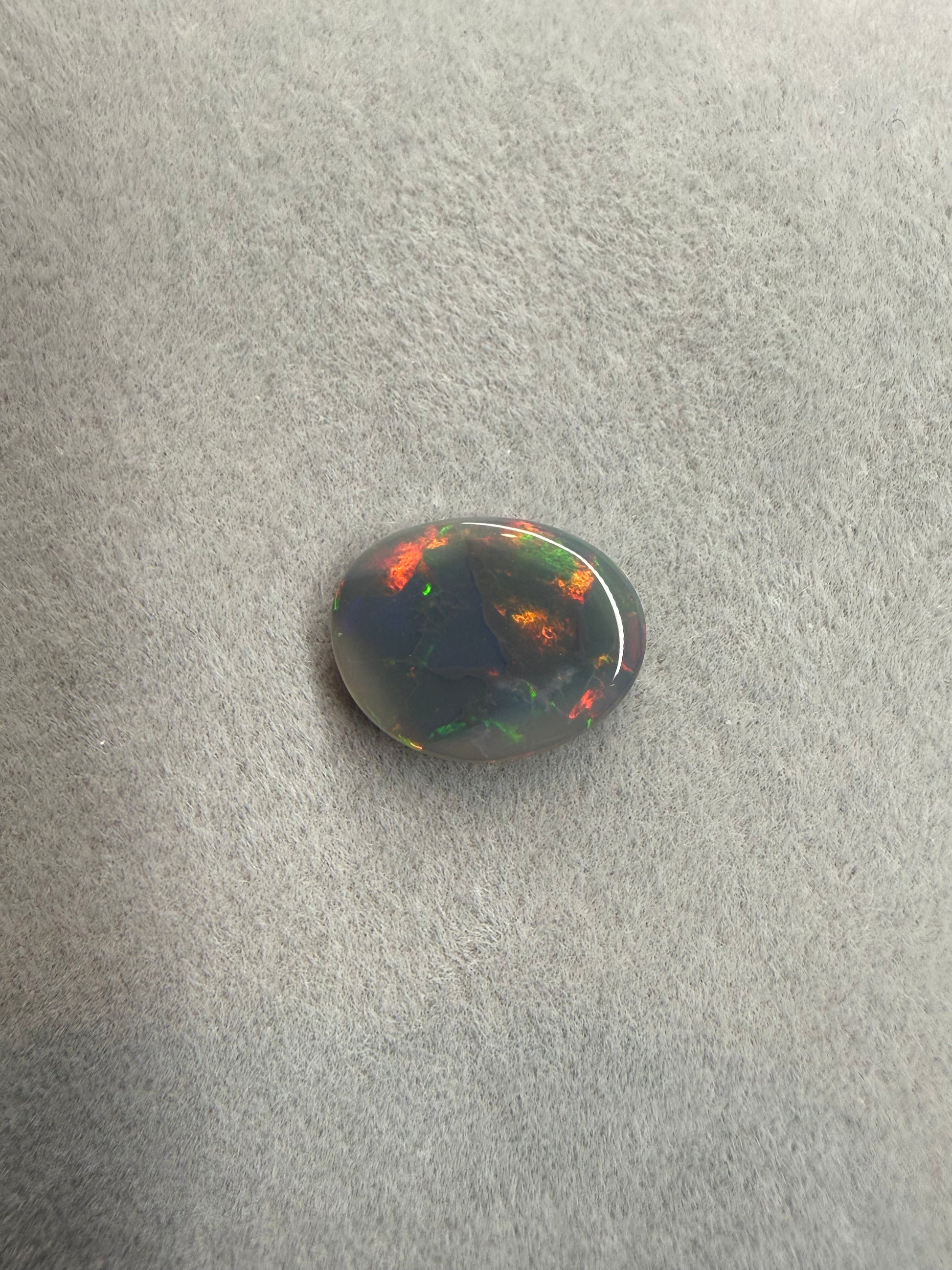 Australischer Dark Opal in Freiform mit leuchtenden Grün-, Rot- und Orangetönen.